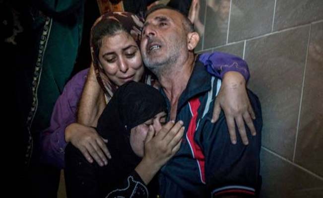 Members of the Abid Raboh family mourn the death of a child killed by shelling, during funerals in Jabaliya near Gaza City. Photograph: Sergey Ponomarev/The New York Times