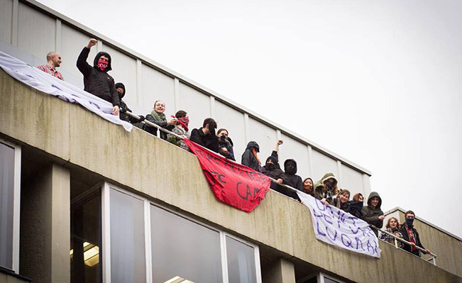 Occupiers, pictured, on the balcony of Bramber House and flying banners while chanting: 'Don’t deport Luqman'.