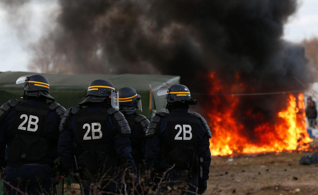 French police watch as huts burn