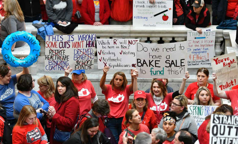 Striking teachers inside the Kentucky state Capitol building holding placards