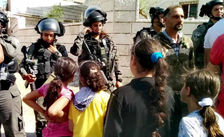 Palestinian children face Israeli soldiers at the house demolition protest in al-Walaja.