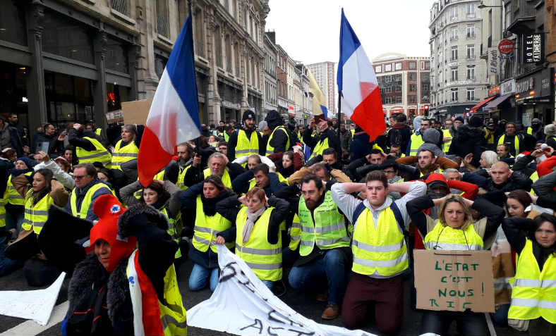 Gilets Jaunes in Lille on Saturday 8 December in mass solidarity gesture with the detained high school students of Mantes-la-Jolie, of whom around a hundred were put in the stress position illustrated when detained by armed police following their protest. Photo: @GiletsJaunes_FR