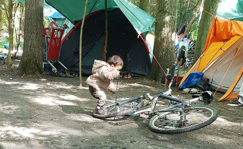 A child plays with a bicycle in a refugee camp in Dunkirk. Photo: Oxfordshire Refugee Solidarity