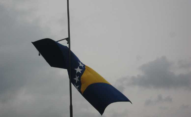 Bosnian flag at the Srebrenica Genocide Commemoration. Photo: the Advocacy Project on flickr/cropped from original/licensed under CC2.0, linked at bottom of article