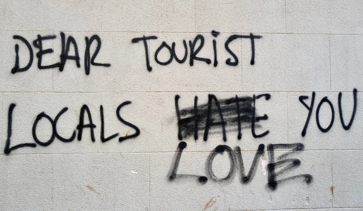 Graffiti in Barcelona saying 'DEAR TOURISTS LOCALS HATE/ LOVE YOU'