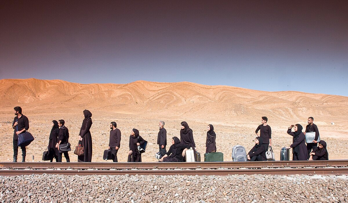 Refugees wait at the side of a railway track